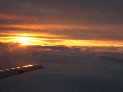 Sonnenaufgang zwischen Wolken im Flug ber die Alpen